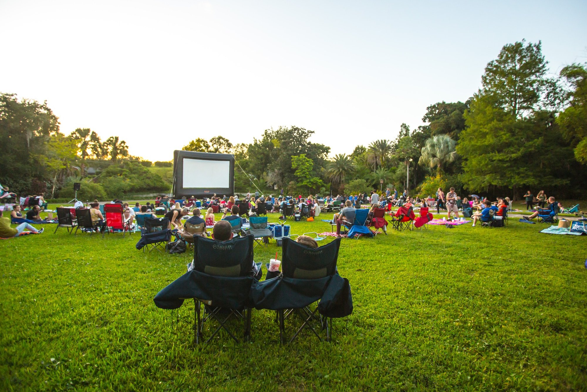 chairs and blankets on a lawn outdoors with movie screen
